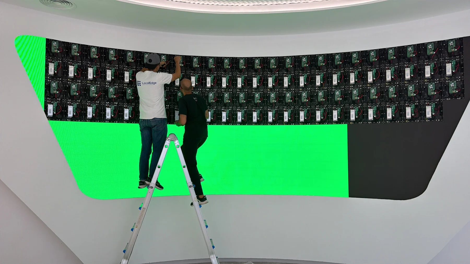 Techniciens installant les modules d'un mur LED incurvé dans un showroom automobile